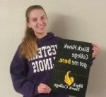 student wearing a Western Illinois University shirt holding a BHC sign