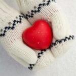 hands in white mittens holding red heart