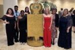 7 people dressed up & standing by large Phi Theta Kappa gold key emblem